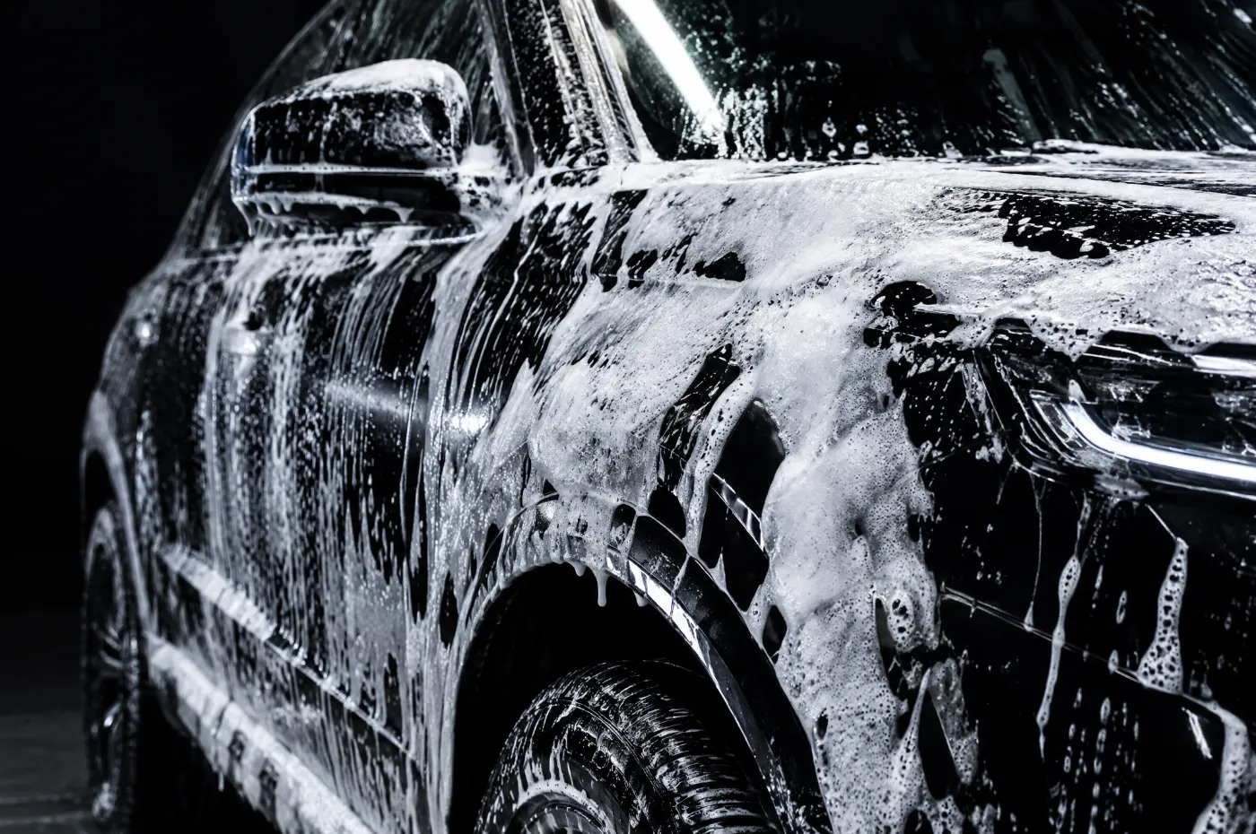 Snow foam running down the side of a black car
